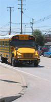 Yellow school bus on road, with blue sky, in daylight. School buses are usually in rush hour traffic. By National Institute for Occupational Safety and Health.
